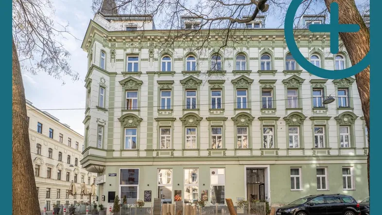 Historisches Gebäude mit reich verzierter Fassade in Grün- und Weißtönen an einer städtischen Straße.