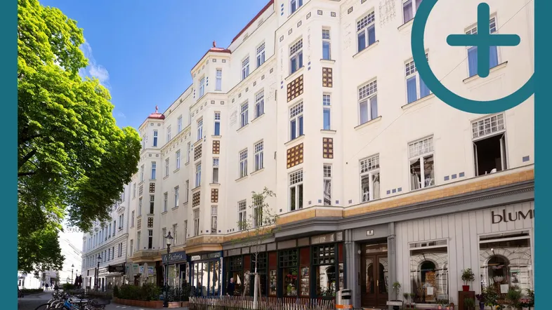 Historisches Gebäude mit eleganter Fassade und Geschäften im Erdgeschoss an einer belebten Straße.