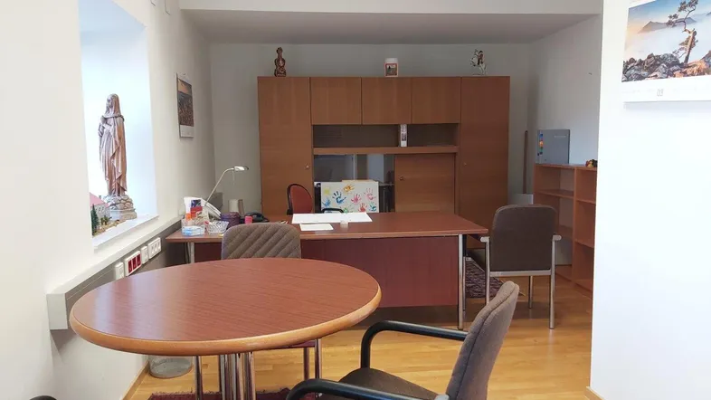 Geräumiges Büro mit Holzboden, großem Schreibtisch und Besprechungstisch, ausgestattet mit Holzschränken.