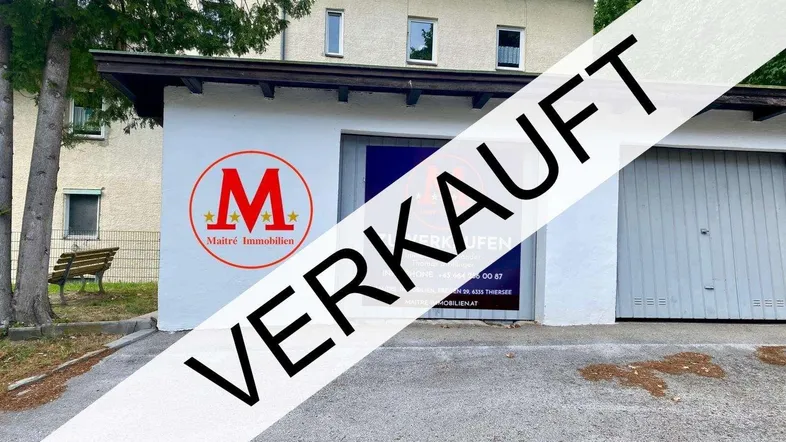 Außenansicht der Garage mit einem "VERKAUFT"-Banner und dem dahinterliegenden Wohngebäude.