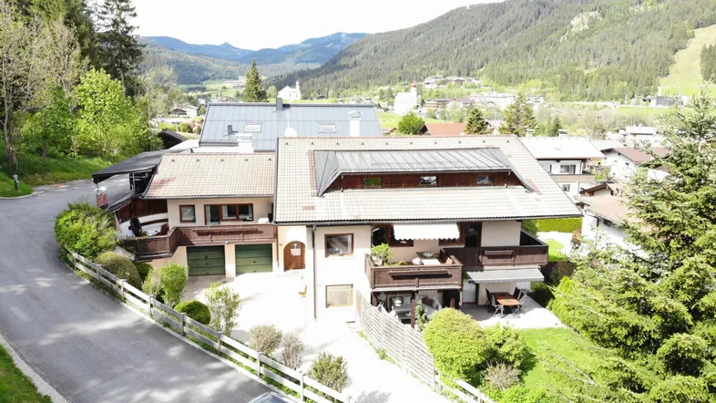 Großzügiges Wohnhaus in alpiner Umgebung mit mehreren Balkonen und Bergblick.