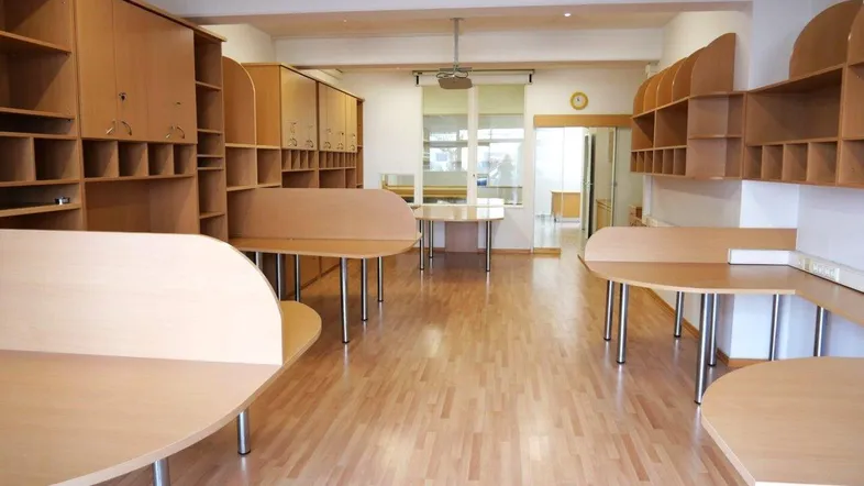 Geräumiger Büroraum mit mehreren Arbeitsplätzen, Holzregalen und hellem Laminatboden.