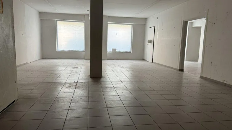 Großer, leerer Gewerberaum mit Fliesenboden, tragenden Säulen und Fenstern, bereit für den Ausbau.
