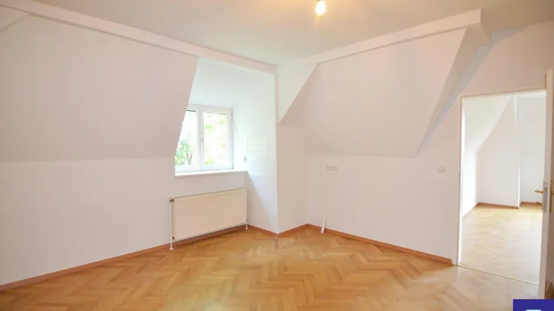 Helles Dachgeschosszimmer mit Fischgrätparkett, Fenster und schrägen Wänden, bereit zur individuellen Gestaltung.