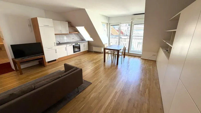 Heller offener Wohn-Essbereich mit integrierter Küche, Holzfußboden und Zugang zum Balkon.