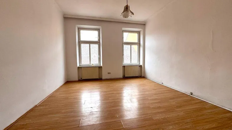 Helles Zimmer mit Laminatboden und zwei Fenstern, bereit für die individuelle Gestaltung.