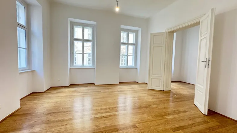 Helles Zimmer mit schönem Parkettboden und hohen Fenstern, bereit zur individuellen Gestaltung.