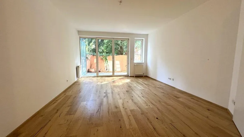 Helles Wohnzimmer mit Holzboden und Zugang zu einer Terrasse oder Gartenbereich.