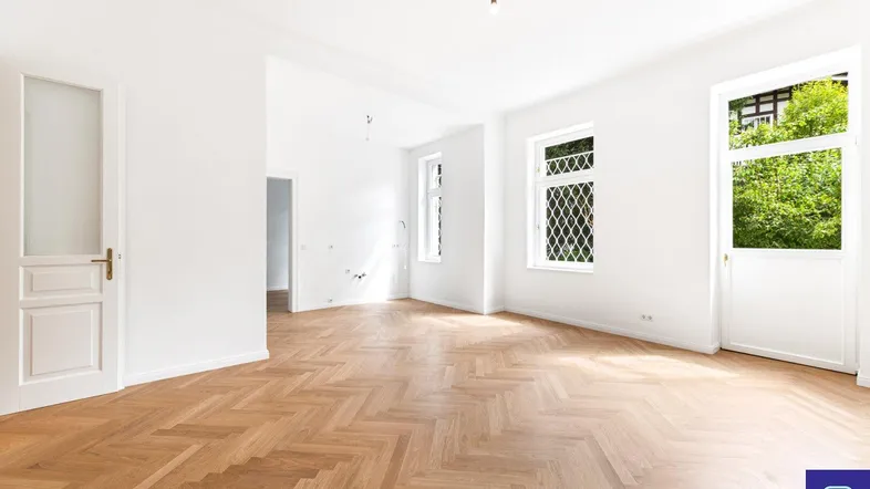 Helles, leeres Zimmer mit Fischgrätparkett und hohen Fenstern, bereit zur individuellen Gestaltung.