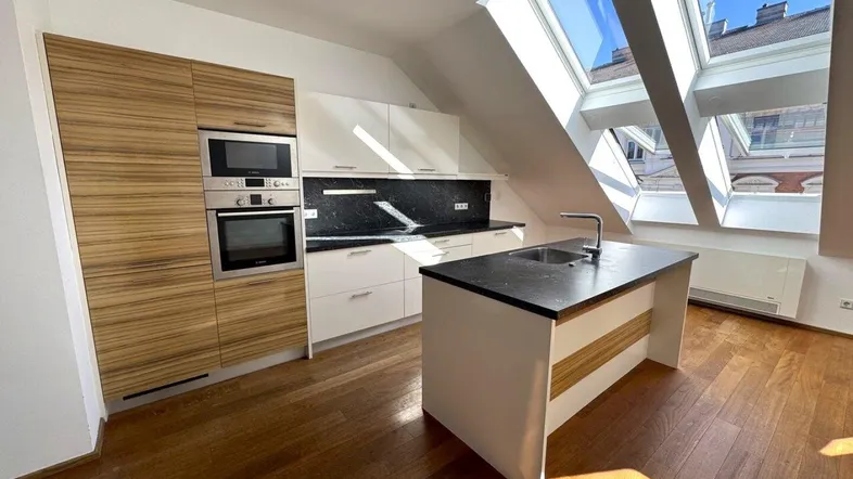 Moderne Küche mit Holzelementen, integrierten Geräten und einer Kücheninsel unter großen Dachfenstern.