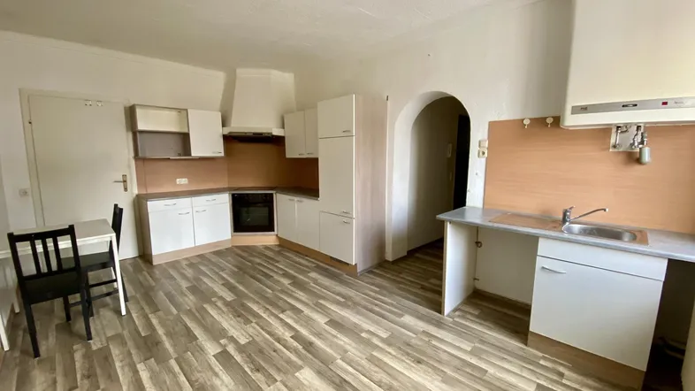 Funktionale Küche mit weißen Schränken, Laminatboden und Essbereich.