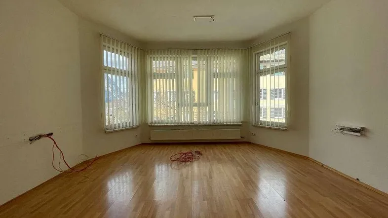 Heller Wohnraum mit Parkettboden und großen Fenstern, bereit für die individuelle Gestaltung.