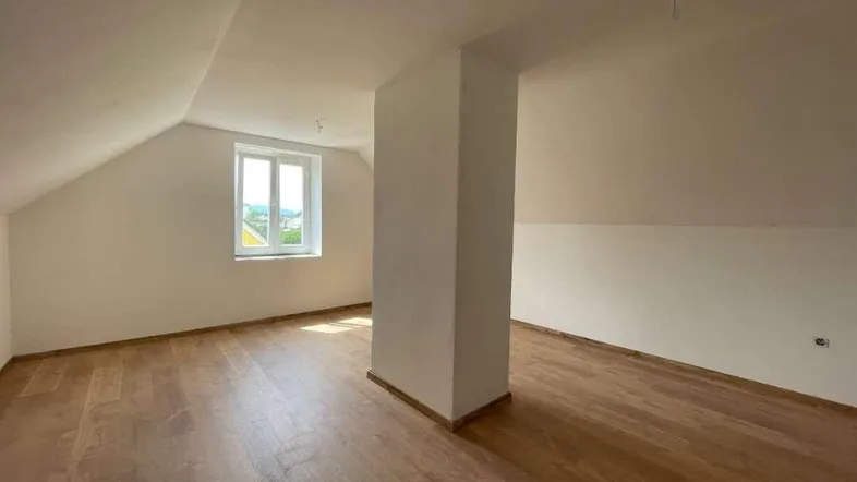 Heller Raum im Dachgeschoss mit Holzboden und schräger Decke, ideal für individuelle Gestaltung.