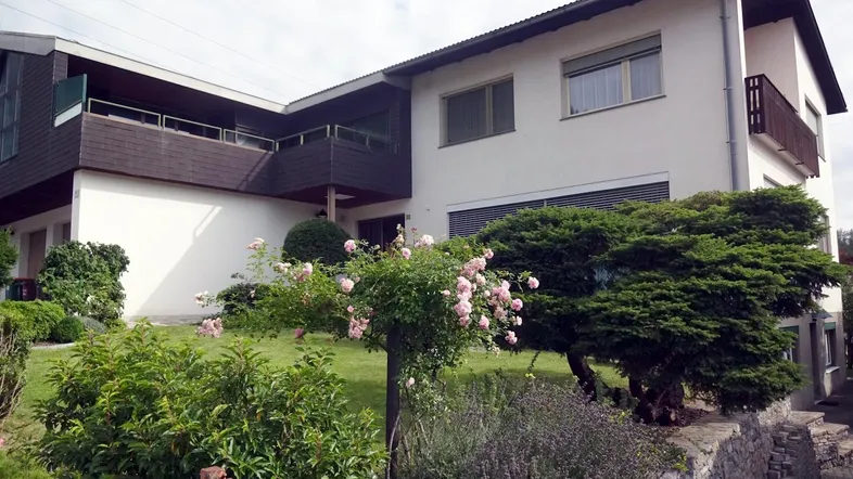 Mehrfamilienhaus mit gepflegtem Vorgarten, blühenden Rosen und Balkonen.