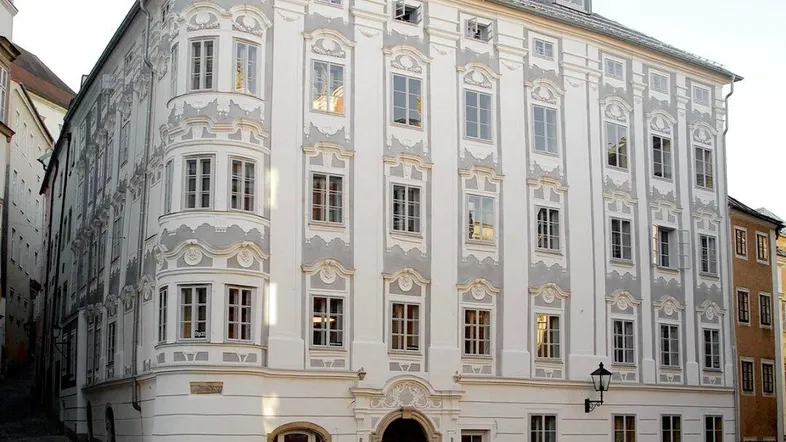 Historisches Eckgebäude mit aufwendiger Stuckfassade und vielen Fenstern in einer städtischen Umgebung.
