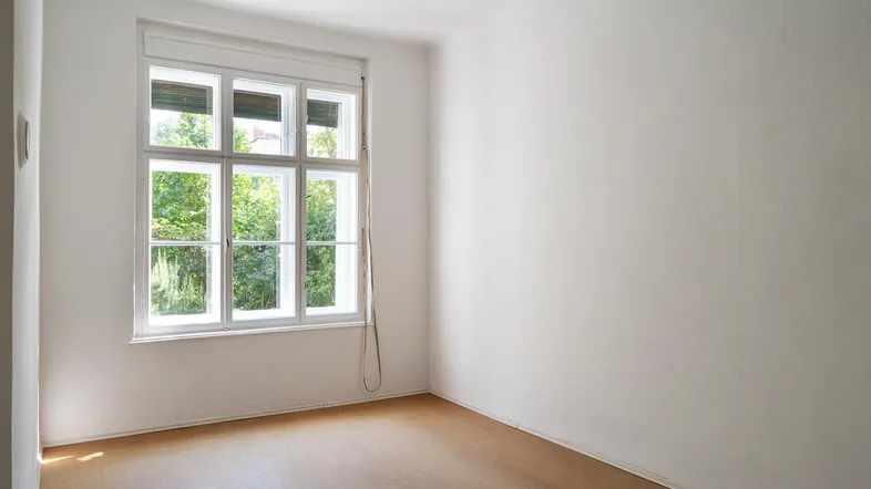 Helles Zimmer mit großem Fenster und Blick ins Grüne, ausgestattet mit Rolladen.