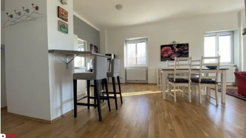 Heller Wohn- und Essbereich mit Holzboden, Frühstücksbar und Esstisch, ideal für geselliges Beisammensein.
