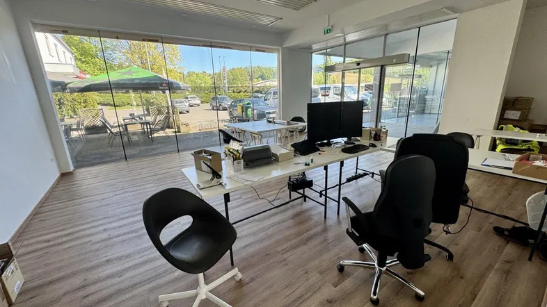 Geräumiges Büro mit großen Glasfronten, die viel Tageslicht hereinlassen und einen Blick nach draußen bieten.