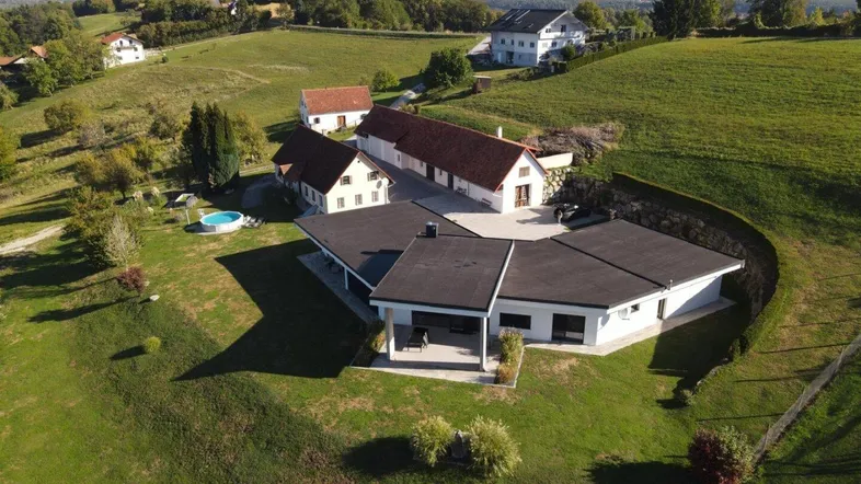 Luftaufnahme eines Anwesens mit mehreren Gebäuden, weitläufigen Grünflächen und einem Pool.