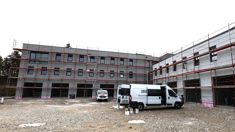 Neubau im Bauzustand mit Gerüst und Baufahrzeugen auf dem Schotterplatz.