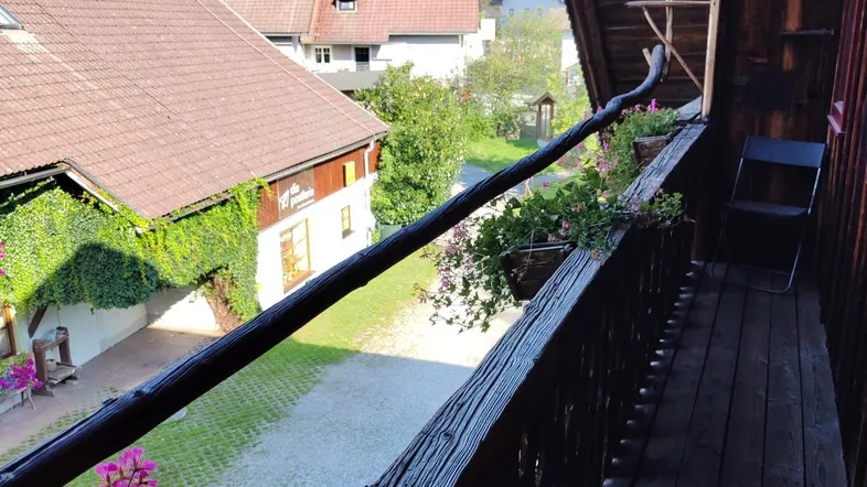 Traditioneller Holzbalkon mit Blumenkästen bietet einen Blick auf den Innenhof und die umliegenden Häuser.