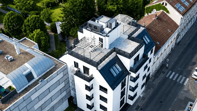 Moderne Wohnanlage von oben mit Flachdach und Dachterrassen in grüner Umgebung.