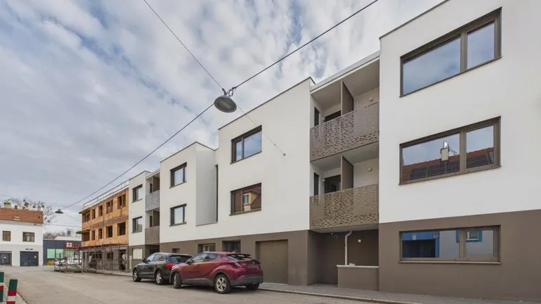 Moderne Wohngebäude mit weißer und brauner Fassade entlang einer ruhigen Straße.