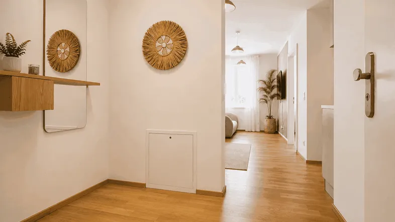 Heller Eingangsbereich mit Holzfußboden, modernem Spiegel und Zugang zum Wohnbereich.