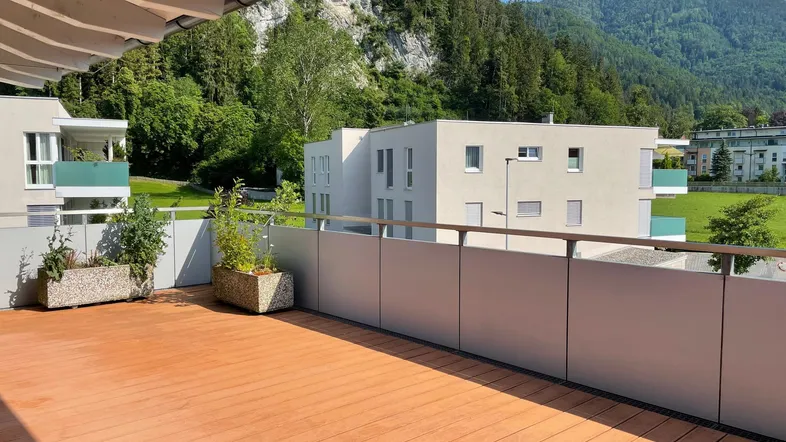 Große Terrasse mit Holzboden, Pflanzen und einem weiten Blick auf die umliegende Berglandschaft.