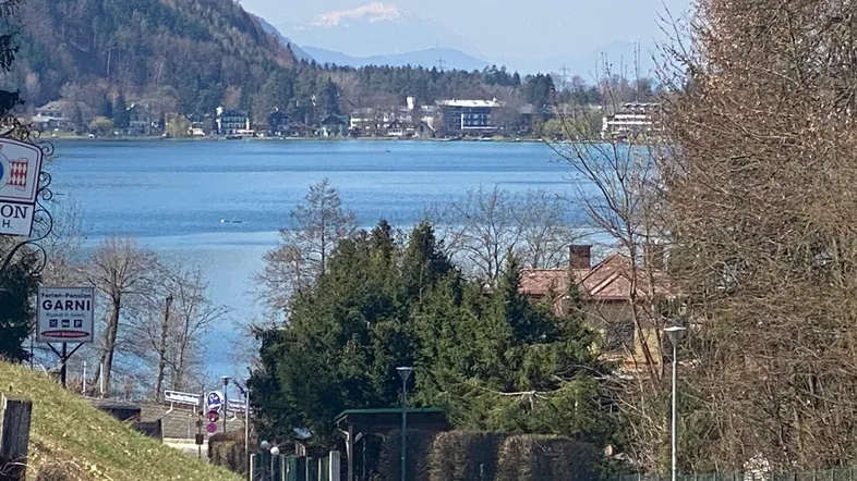 Panoramablick auf den See und die umliegenden Berge mit bewaldeten Hängen unter klarem Himmel.