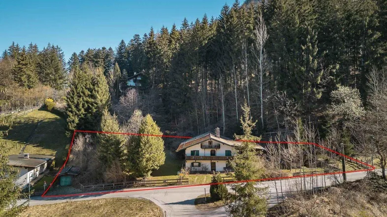 Charmantes Haus im alpinen Stil, umgeben von Wald und Natur, mit markierten Grundstücksgrenzen.