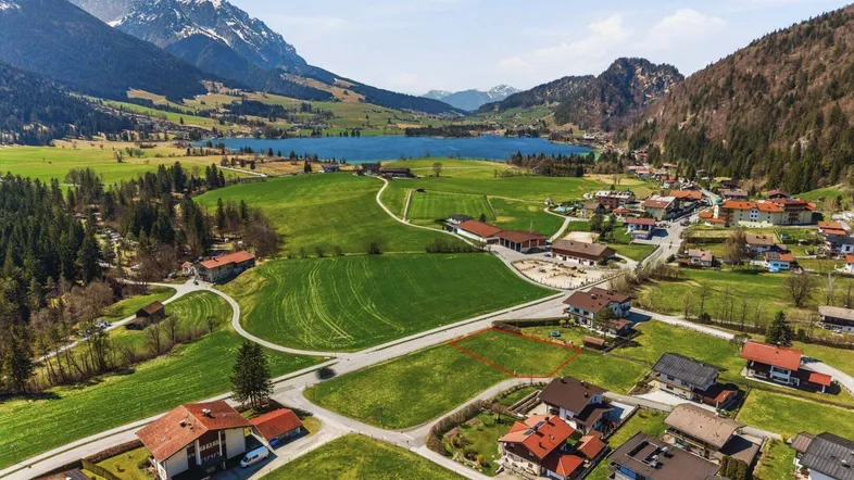 Luftaufnahme eines Baugrundstücks mit malerischem See- und Bergblick in ländlicher Umgebung.