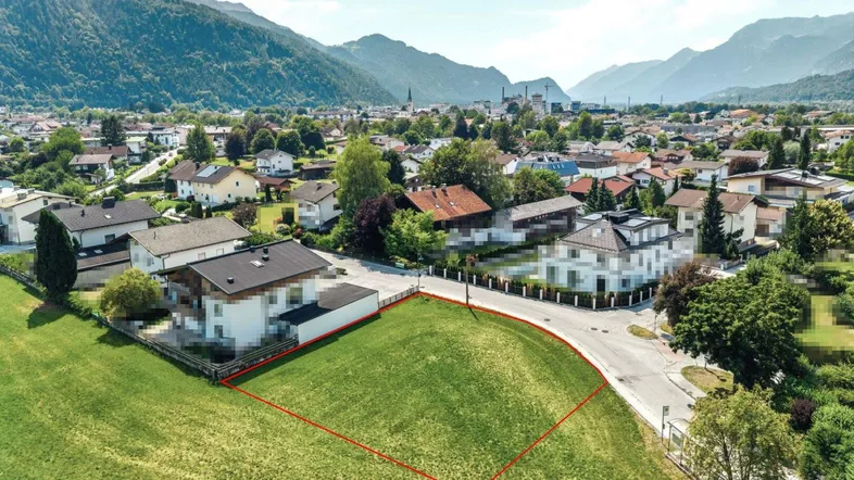 Luftaufnahme eines Baugrundstücks in einer Wohngegend mit Bergblick und grüner Umgebung.