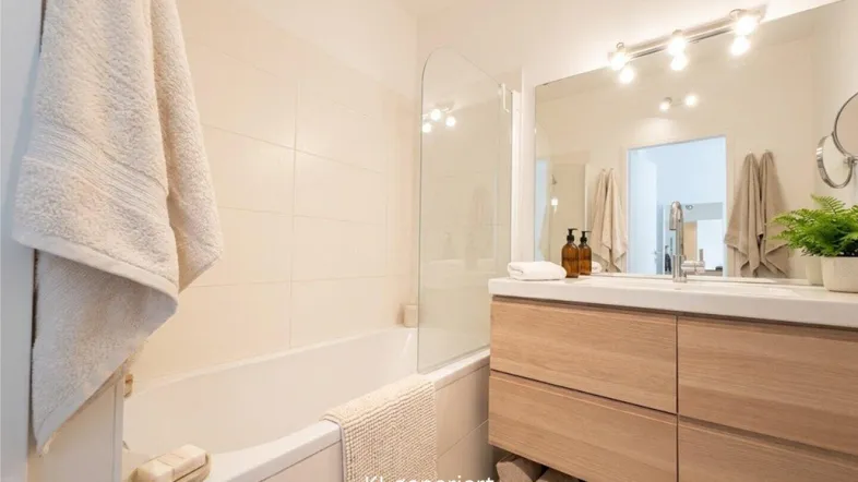 Modernes Badezimmer mit Badewanne, Holzwaschtisch, großem Spiegel und beheiztem Handtuchhalter.