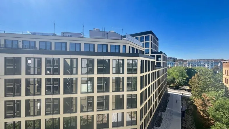 Moderne Wohngebäude mit vielen Fenstern unter strahlend blauem Himmel.