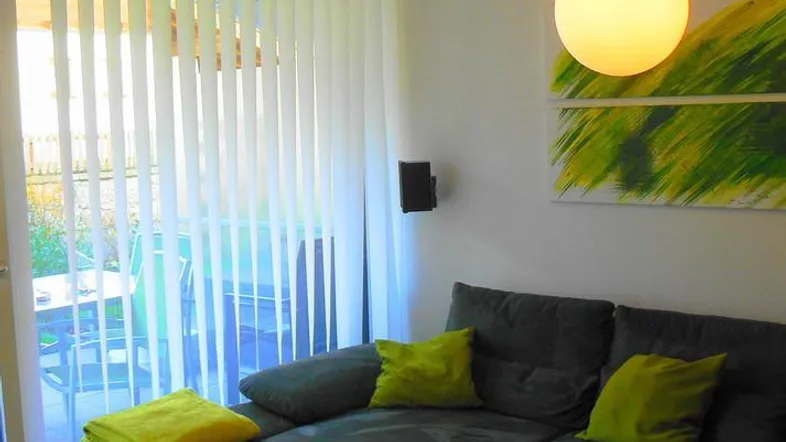 Modernes Wohnzimmer mit bequemer Eckcouch, farbigen Kissen und Zugang zu einem Außenbereich.