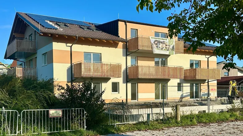 Modernes Mehrfamilienhaus mit Balkonen, Photovoltaikanlage auf dem Dach und farbiger Fassadengestaltung.