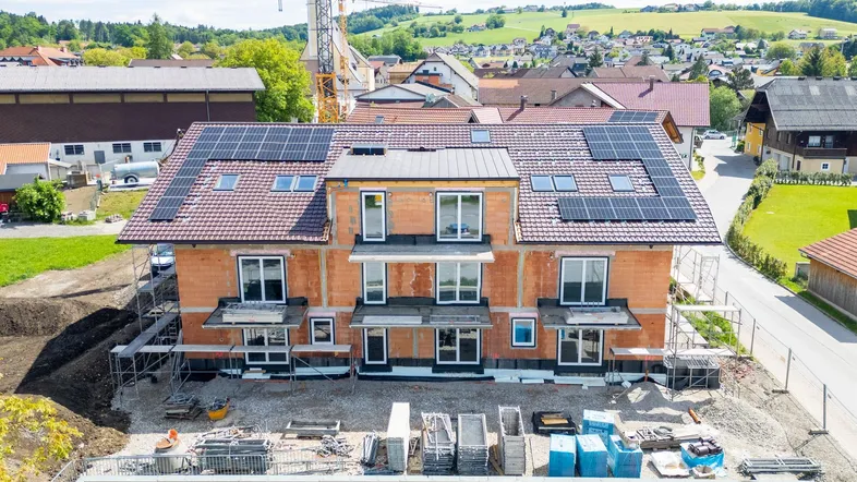 Neubau eines Mehrfamilienhauses in Massivbauweise mit installierter Photovoltaikanlage und Blick ins Grüne.