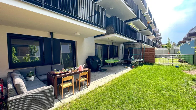Gepflegter Gartenbereich mit Terrasse und Sitzgelegenheiten vor einem modernen Wohngebäude.