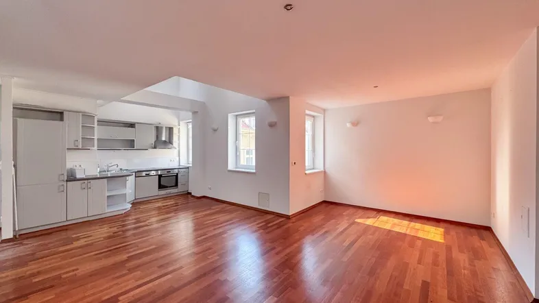 Heller offener Wohnbereich mit integrierter Küche und warmem Parkettboden, ideal für modernes Wohnen.
