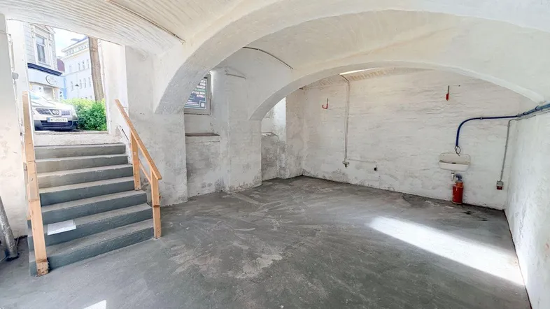 Kellerraum mit Blick auf die Treppe, die zum Straßenniveau führt, und gewölbter Deckenkonstruktion.