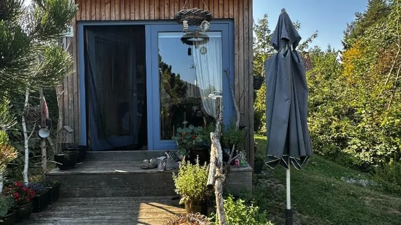Kleines Holzhaus mit moderner Architektur und Zugang zu einer Holzterrasse.