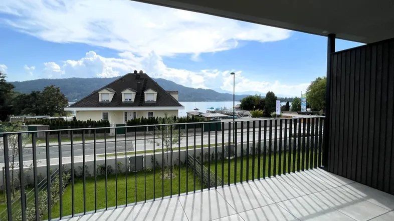 Geräumiger Balkon mit Fliesenboden und weitem Blick auf den See und die umliegenden Berge.
