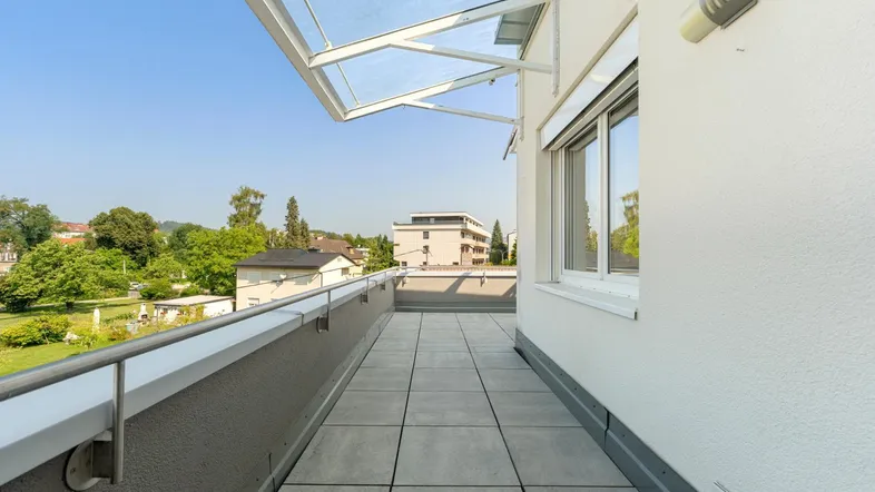 Geräumige, geflieste Terrasse mit Glasüberdachung und weitem Blick auf die umliegende Wohngegend.