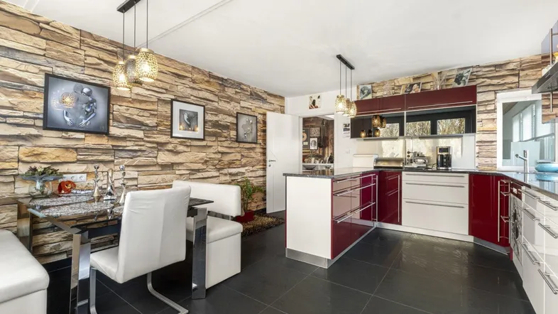 Moderne offene Küche mit Steinwand, dunklen Fliesen und Essbereich für gesellige Stunden.