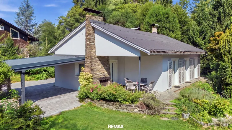 Haus mit Terrasse, Carport und Garten in grüner Umgebung, ideal zum Entspannen.