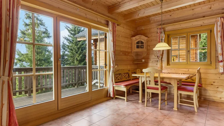 Gemütlicher Essbereich im Chalet-Stil mit Holzwänden, Fliesenboden und Zugang zu einem Balkon mit Bergblick.