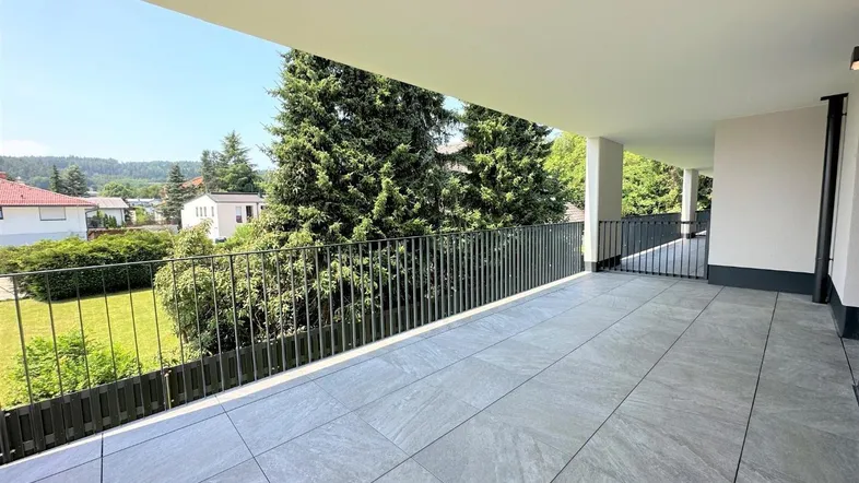 Große, moderne Terrasse mit Fliesenboden und Blick ins Grüne, ideal für Entspannung im Freien.
