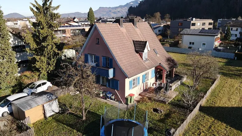 Luftaufnahme eines Einfamilienhauses mit großem Garten, Trampolin und umliegender Wohnbebauung.