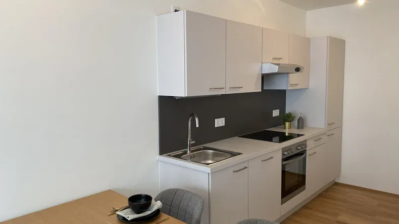 Moderne Einbauküche mit hellen Schränken und integrierten Geräten, kombiniert mit einem Essbereich.